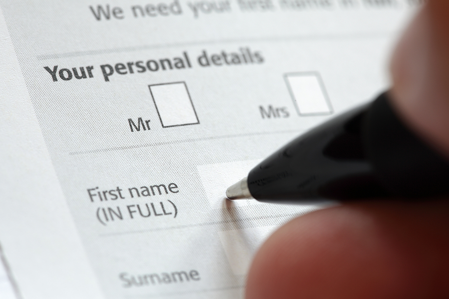 Close-up of a person filling out a personal details form with a pen, writing their first name.