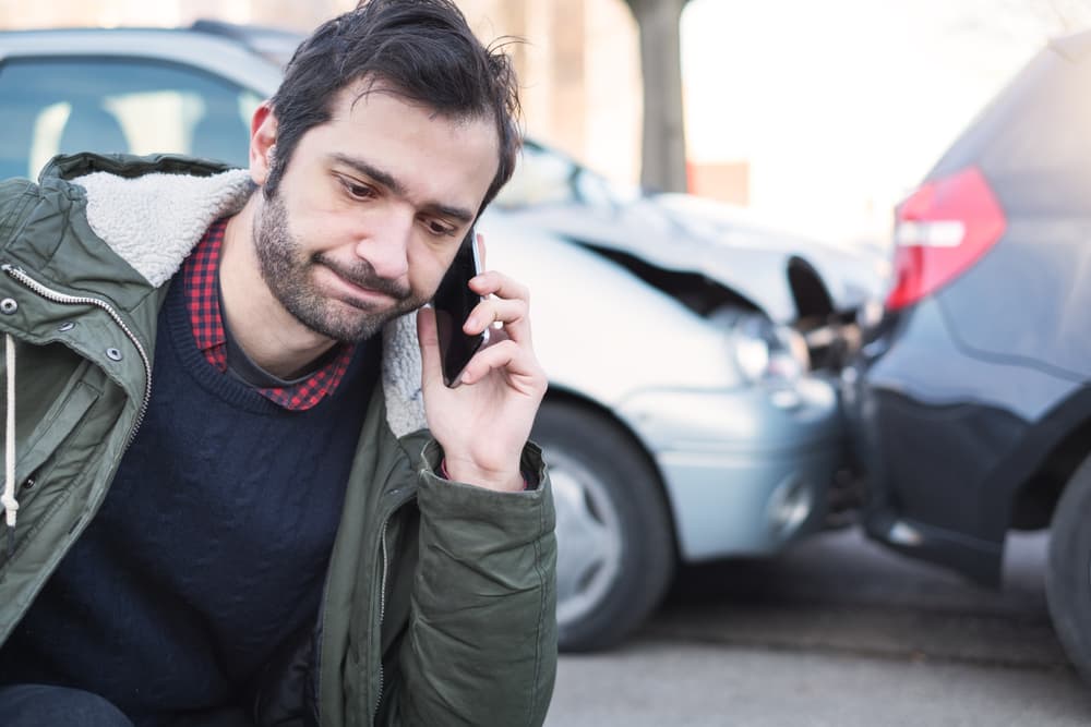 Man calling for first aid assistance after a car crash accident