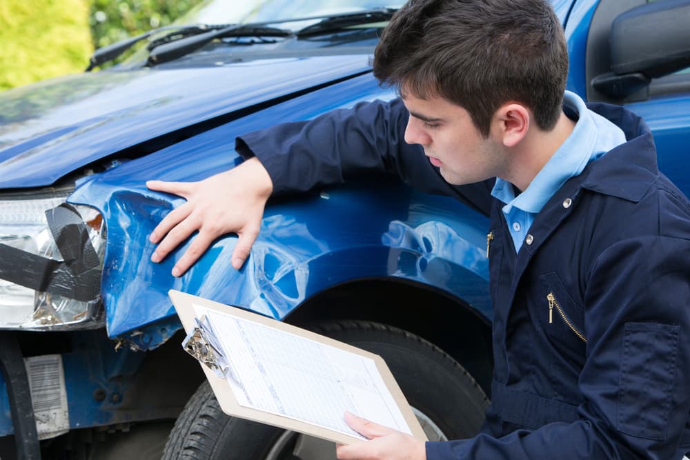 Mechanic at an auto workshop assesses car damage and prepares a repair estimate.