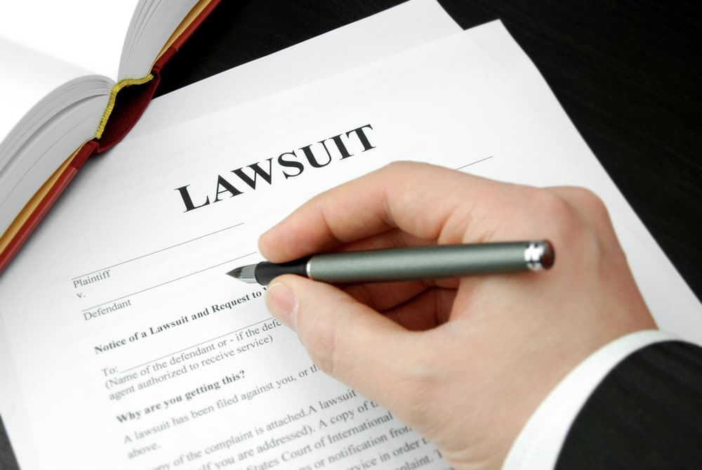 Attorney's hand holding a pen over a lawsuit form.