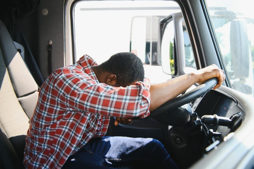 Weary from work, an African American truck driver rests in the cabin during the day, taking a break with his vehicle.