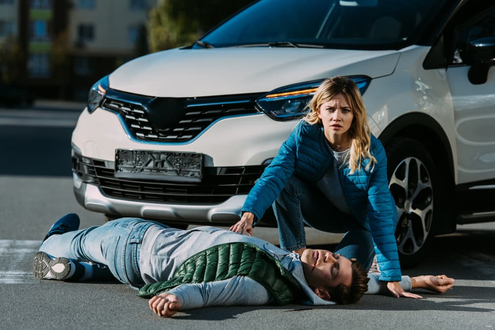 A young woman assesses a victim involved in a motor vehicle collision.