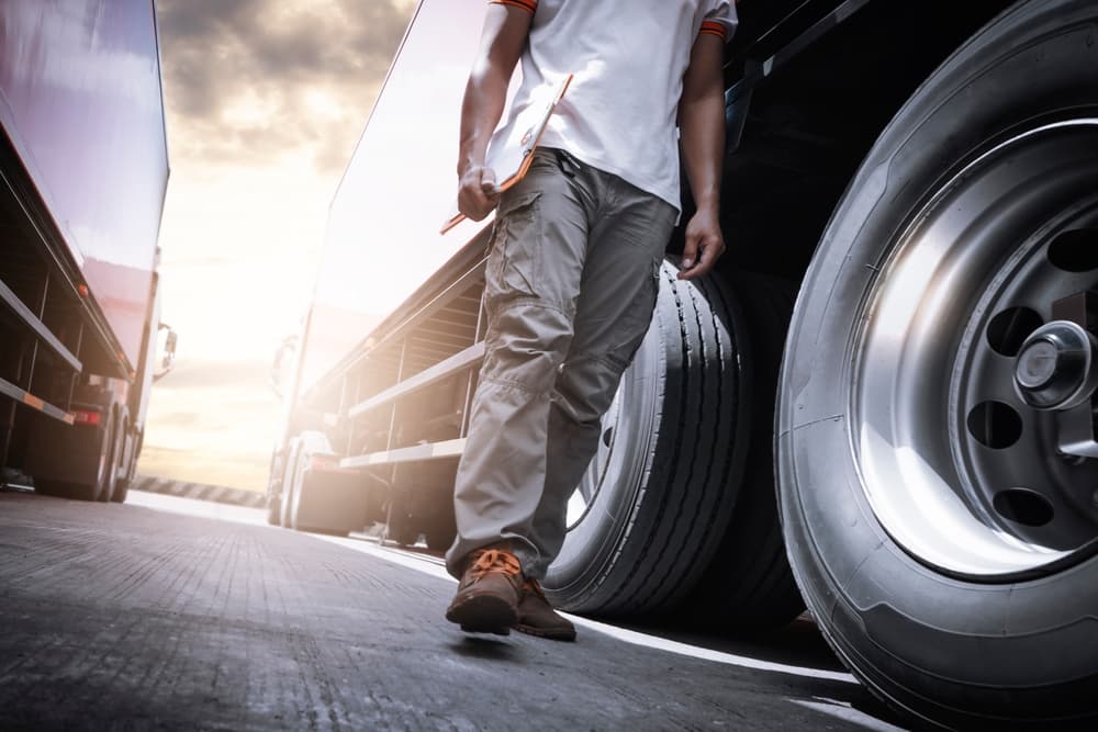 Mechanic inspecting truck wheels and tires for maintenance and safety at an auto service shop.