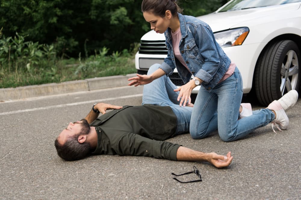 Driver checking on pedestrian after car accident on road, showing concern and assistance