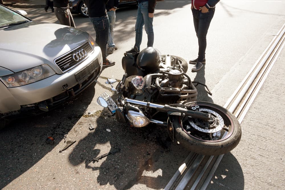 Bicycle collided with car on wet road. Emergency response, police, and insurance involved. Motorcycle accident with car.