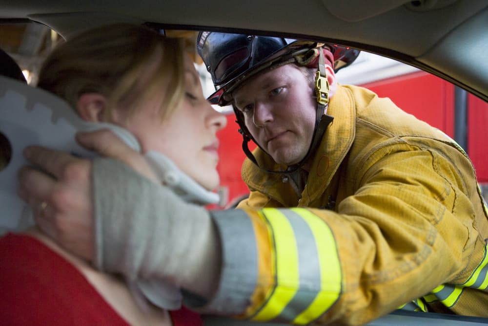 Emergency responders assisting a woman injured in a car accident.