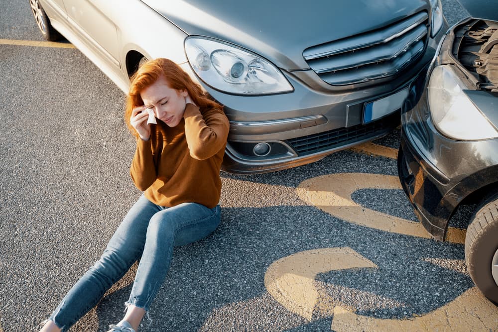 Woman in pain after experiencing a car accident, clutching her injured body.