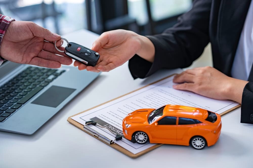 An insurance agent hands over car keys after the tenant signs an auto insurance or lease agreement—completing a new or used car purchase or sale.