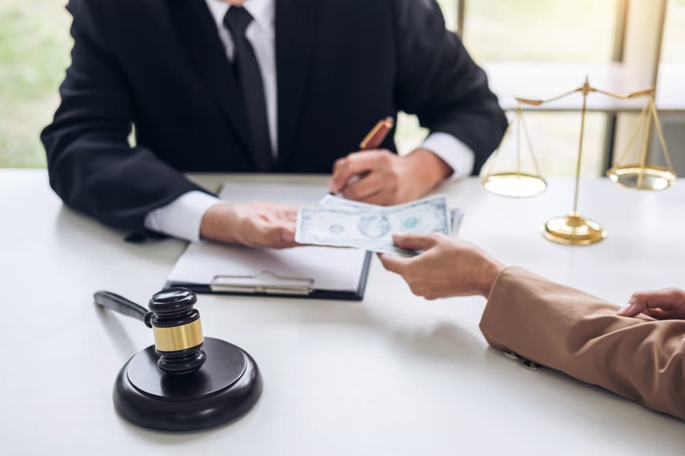 Businesswoman Handing Dollar Bills to a Male Lawyer While Negotiating a Real Estate Contract and Financial Agreement.