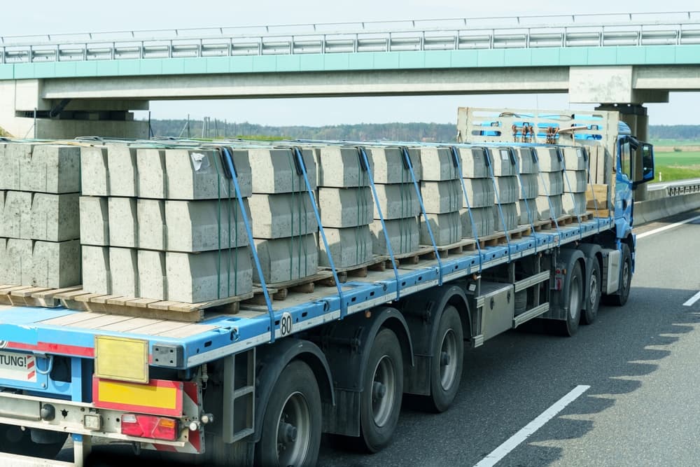 A truck on the highway transports concrete curbs as part of industrial logistics and international trade operations.