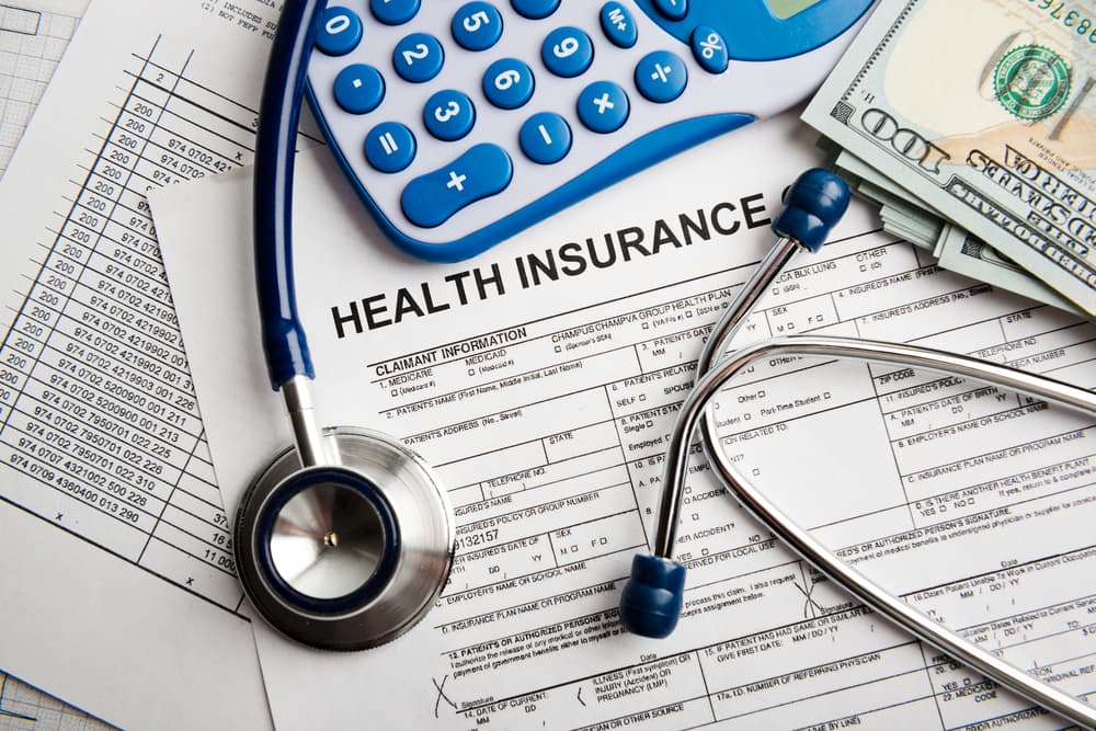 Health insurance application form alongside banknotes and a stethoscope, symbolizing financial planning and life coverage.