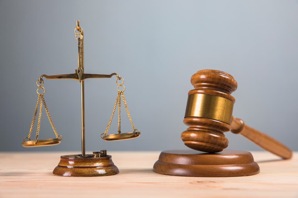 The judge's gavel and a set of scales of justice rest on the table.