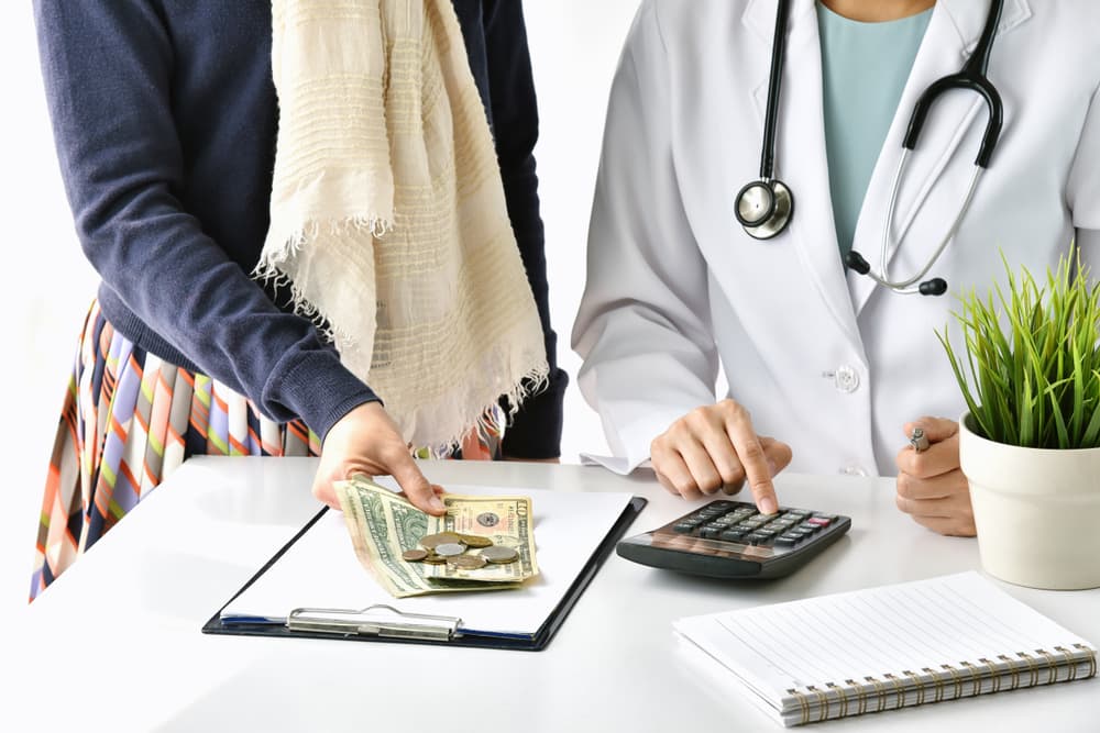 A doctor and a female patient review and calculate medical treatment costs, highlighting hospital expenses and health insurance coverage.