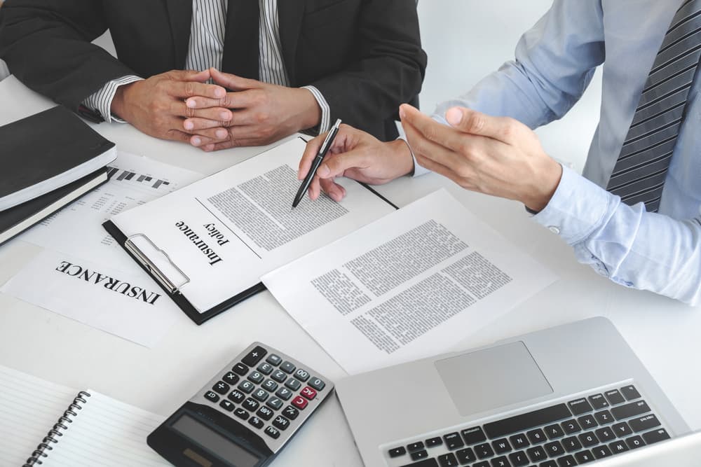 Insurance agent discussing policy details with a customer during a meeting in an office setting.