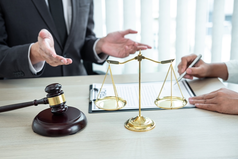 Professional male attorney consulting with a client about a legal case, reviewing contract documents during a meeting in the office. Law, justice, and lawsuit concept.