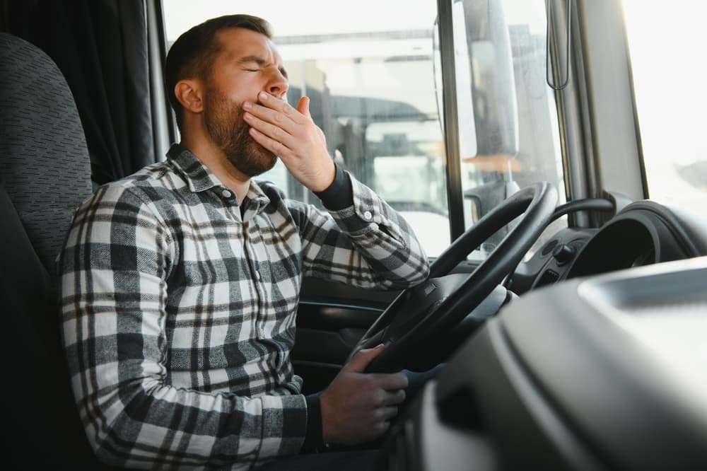 Truck driver struggling with fatigue while driving.